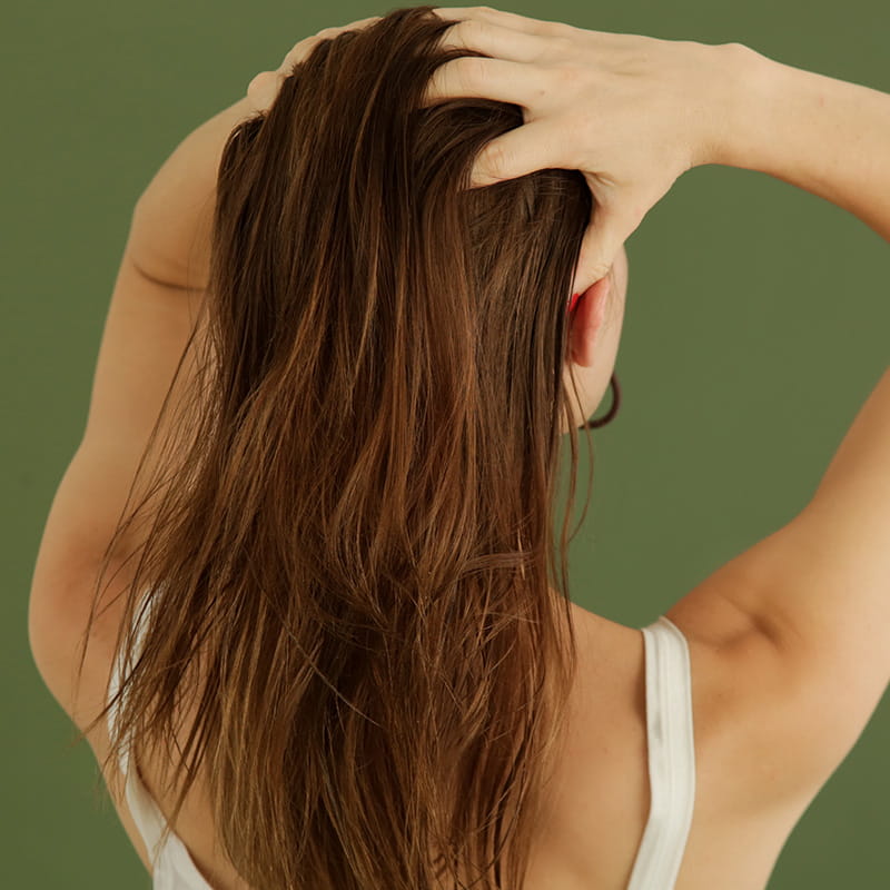 Studio shot of woman applying hair oil with her fingers