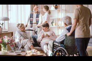 Elderly men and women talking in the common room in nursing home